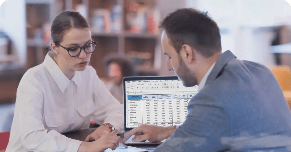 Insurance professionals manually reviewing policy data in spreadsheets during meeting